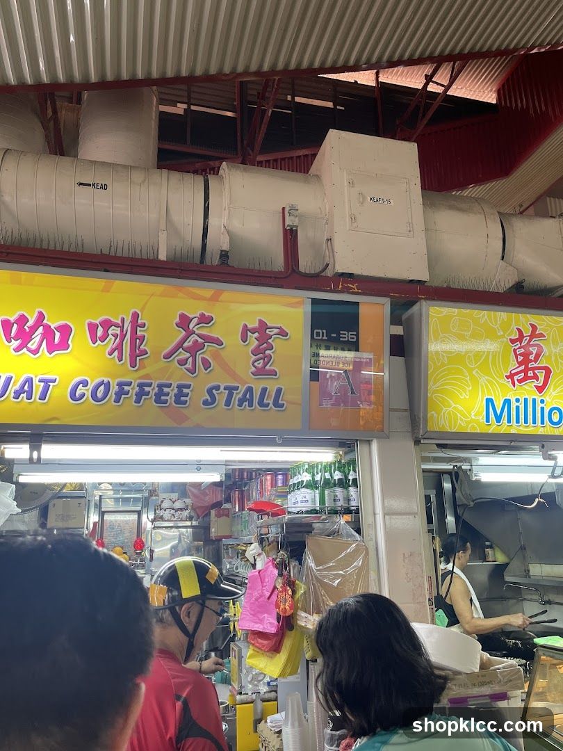 A yellow sign with Chinese characters and the words "JUAT COFFEE STALL" is visible above a food stall. Below the sign, the stall is stocked with drinks and various items. People are queuing at the stall.
