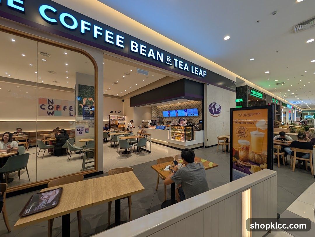 The exterior of a Coffee Bean & Tea Leaf store. The store has large glass windows and a prominent sign above the entrance. Inside, customers are seated at tables and ordering at the counter.