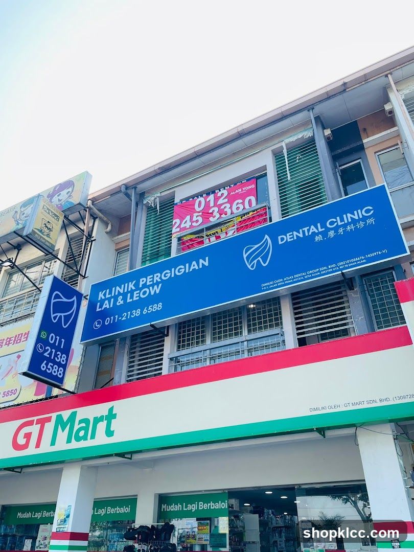 A low-angle exterior shot of a building with multiple businesses. The prominent signage for 'DENTAL CLINIC LAI & LEOW' is visible in blue with white lettering and a tooth logo. Below this, a large red and green sign reads 'GT Mart'. Other smaller signs and windows are also visible.