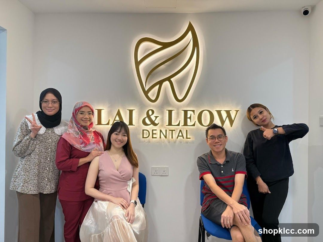 Five individuals, presumably staff members of a dental clinic, pose for a photo in front of a large, illuminated tooth-shaped logo and the text "LAI & LEOW DENTAL". The individuals are smiling and making gestures.