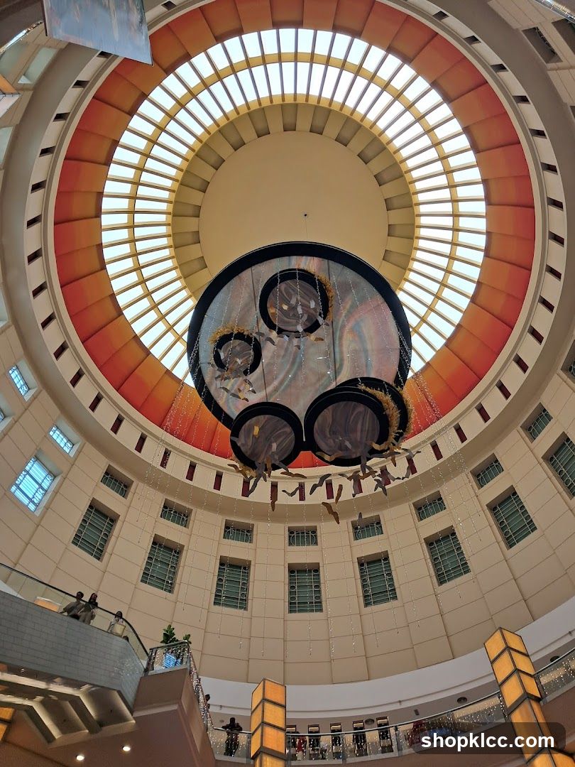Interior of a circular atrium with a large hanging art installation and a skylight.