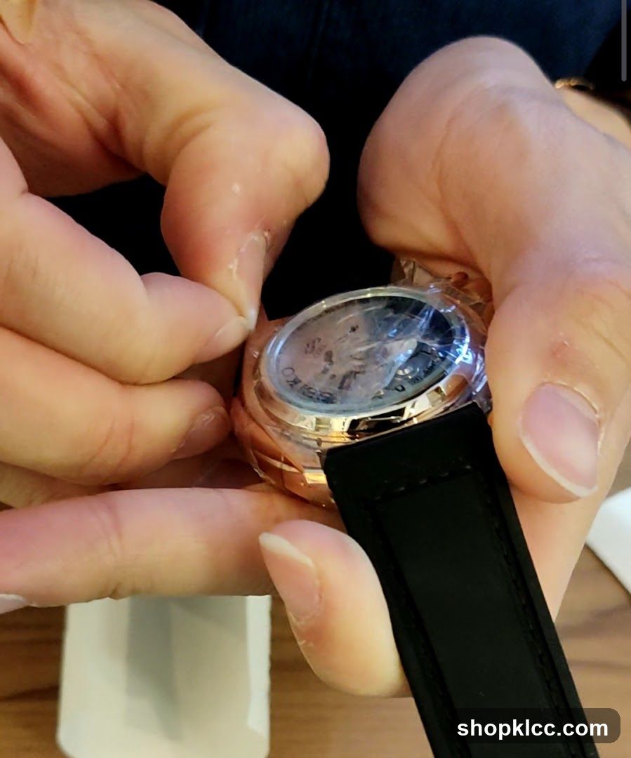 Hands removing protective film from watch