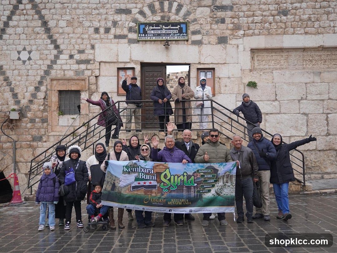 Group posing with a banner in front of a mosque