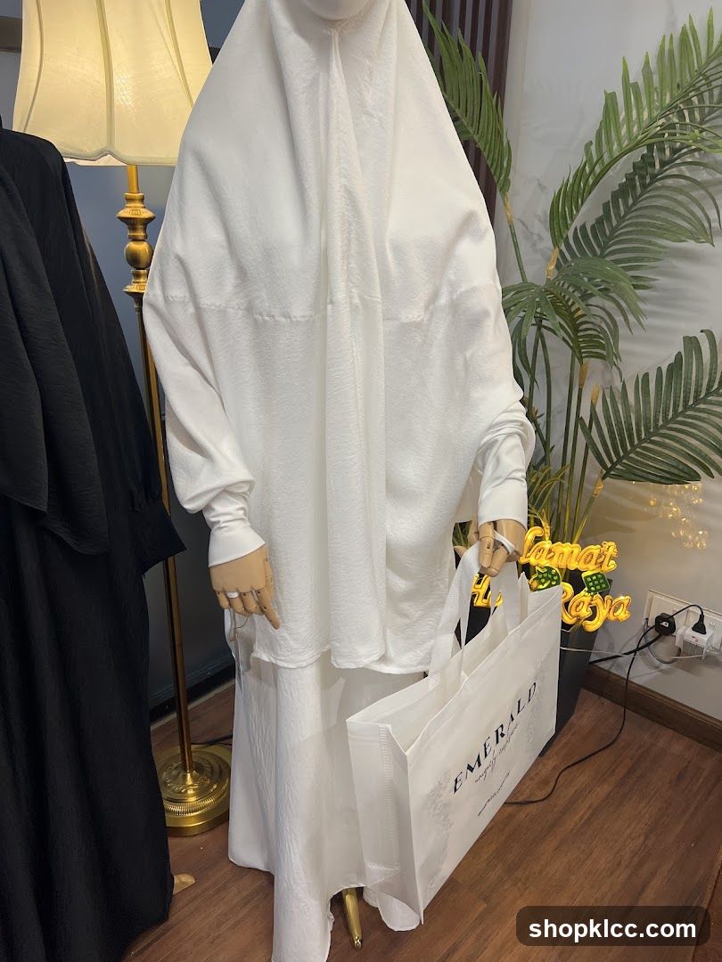 Mannequin in white prayer dress holding a shopping bag