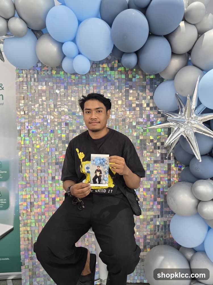 Man holding a photo in front of a balloon arch