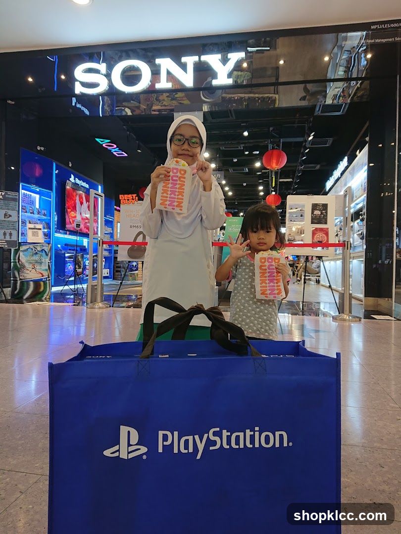 Two children with Dunkin' Donuts boxes in front of a Sony store
