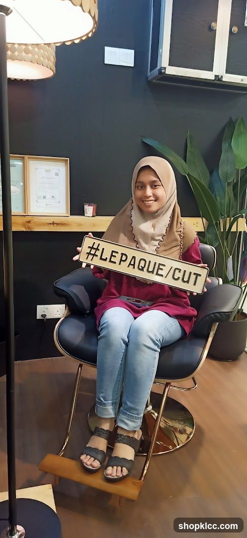 Woman holding a sign with #LEPAQUE/CUT
