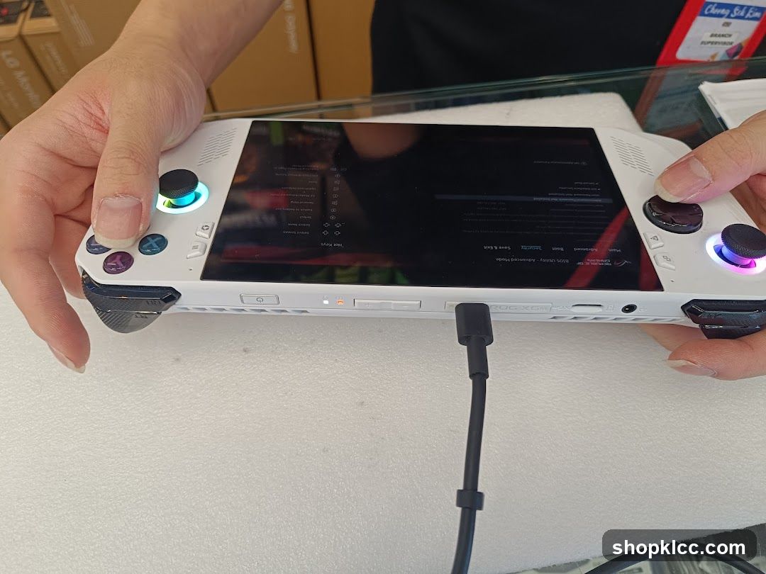 Hand holding a white gaming handheld device