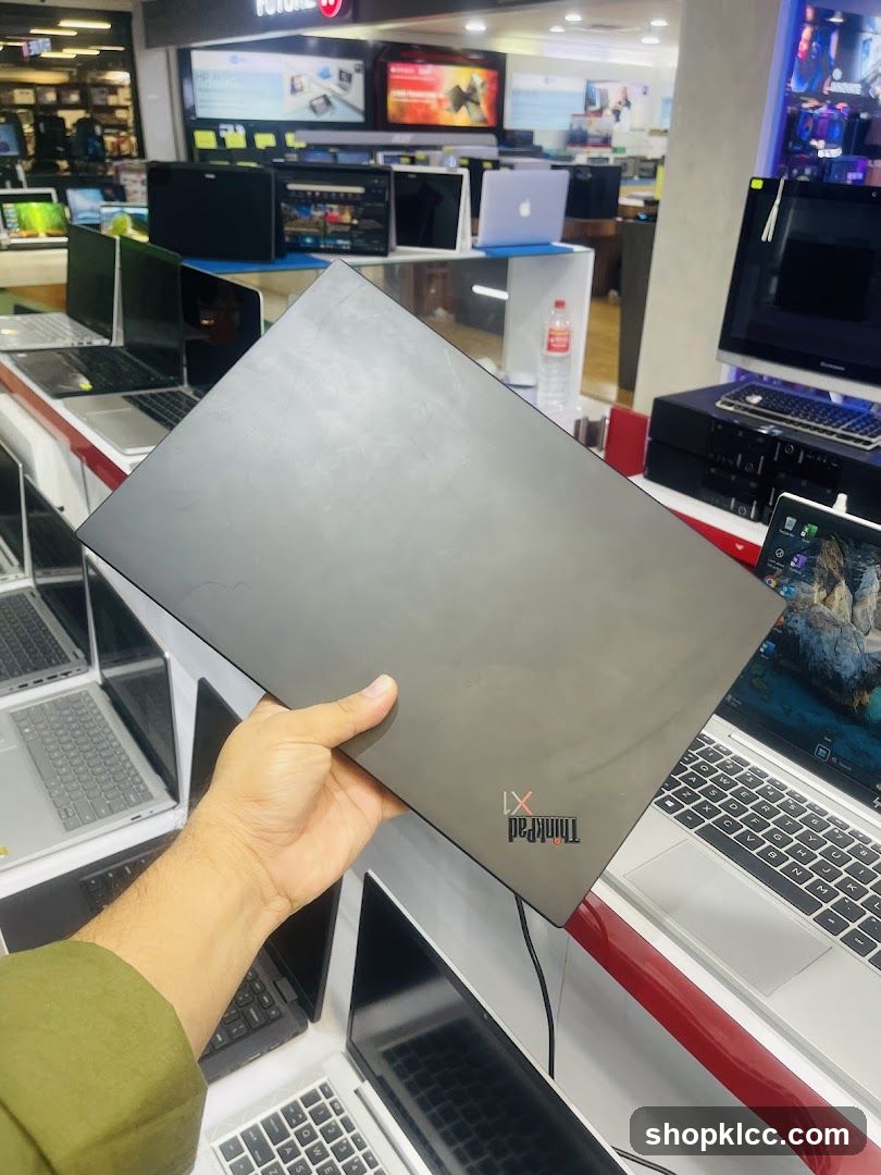 Person holding a laptop in an electronics store