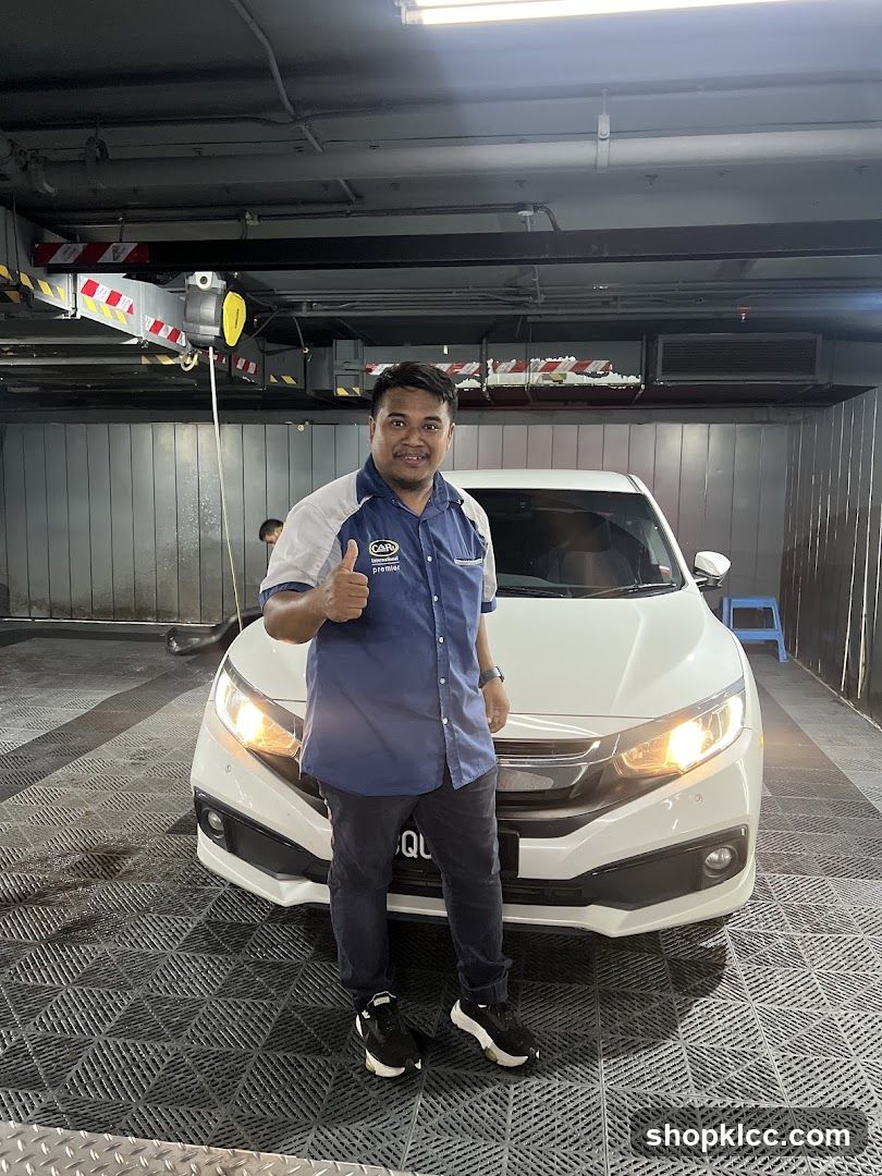 Man giving thumbs up next to a white car