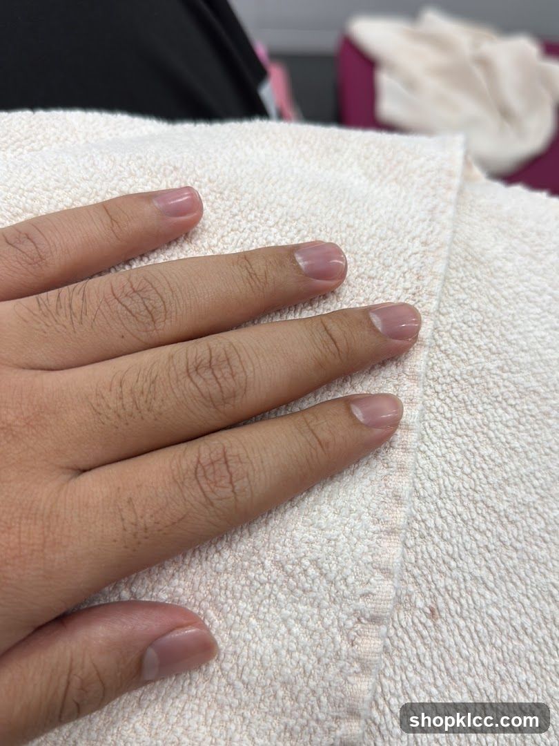 Hand with light pink nails on a towel