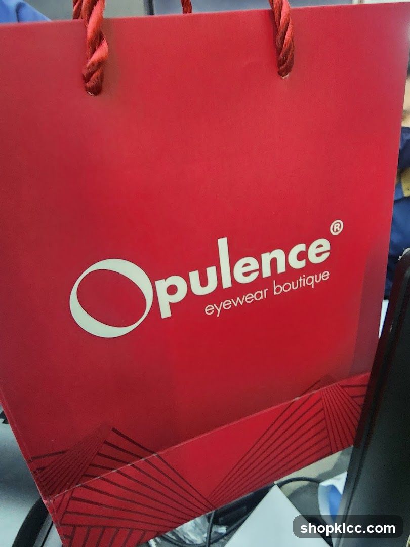 Red shopping bag with "Opulence eyewear boutique" logo