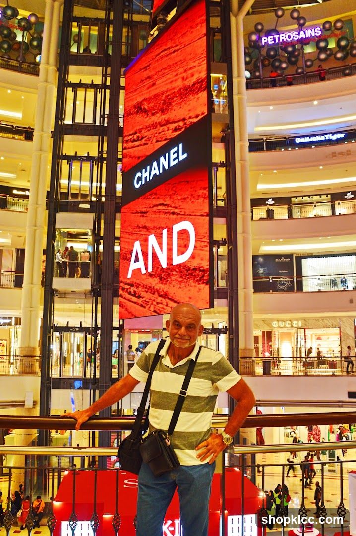 Man Posing in a Mall with a Large Digital Advertisement