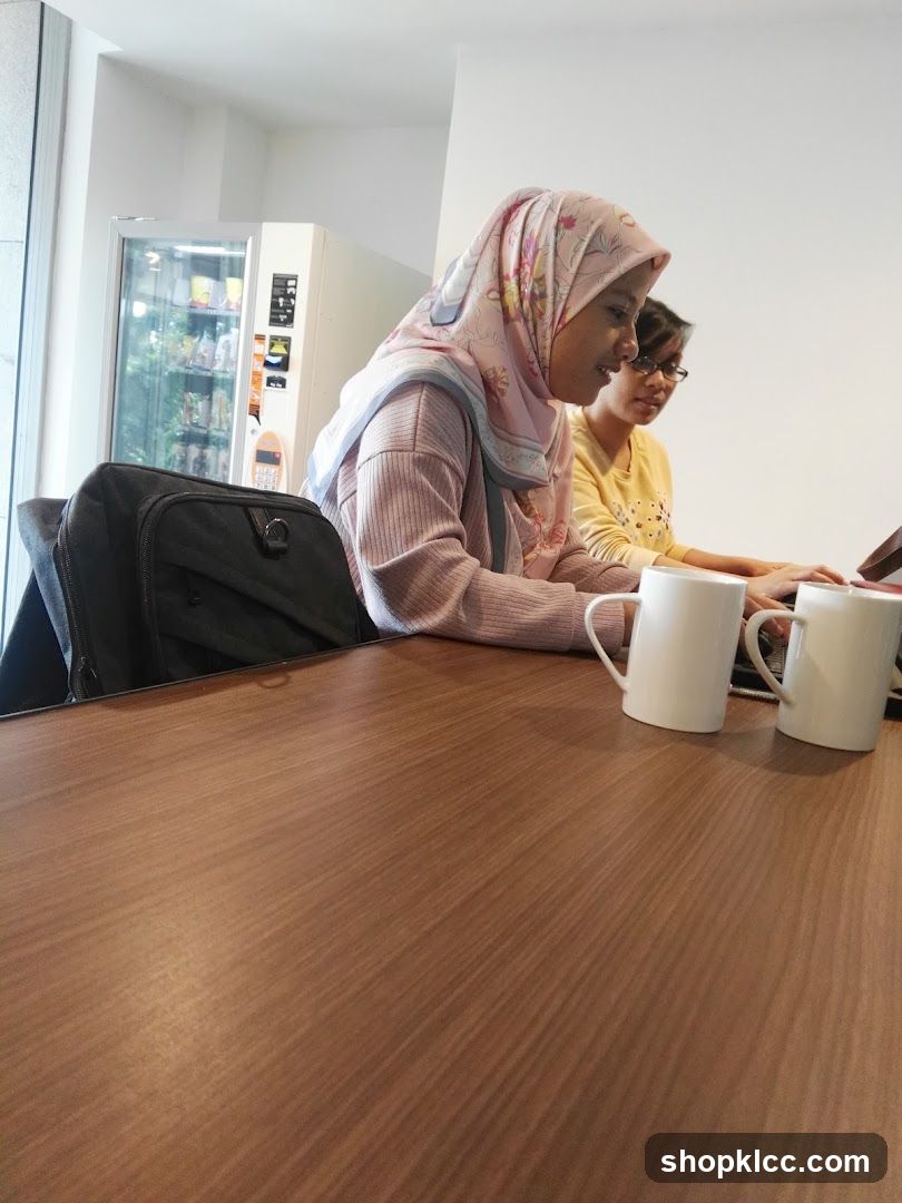 Two women working at a table with a vending machine in the background