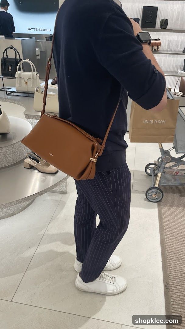 Person carrying a brown handbag in a store