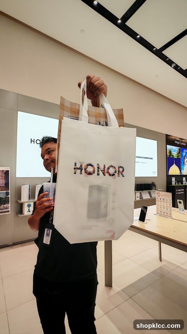 Person holding shopping bags with Honor logo