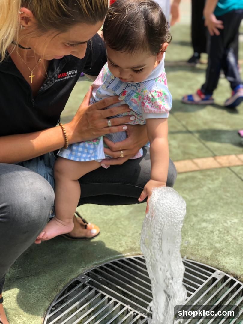 Woman holding a baby near a water fountain