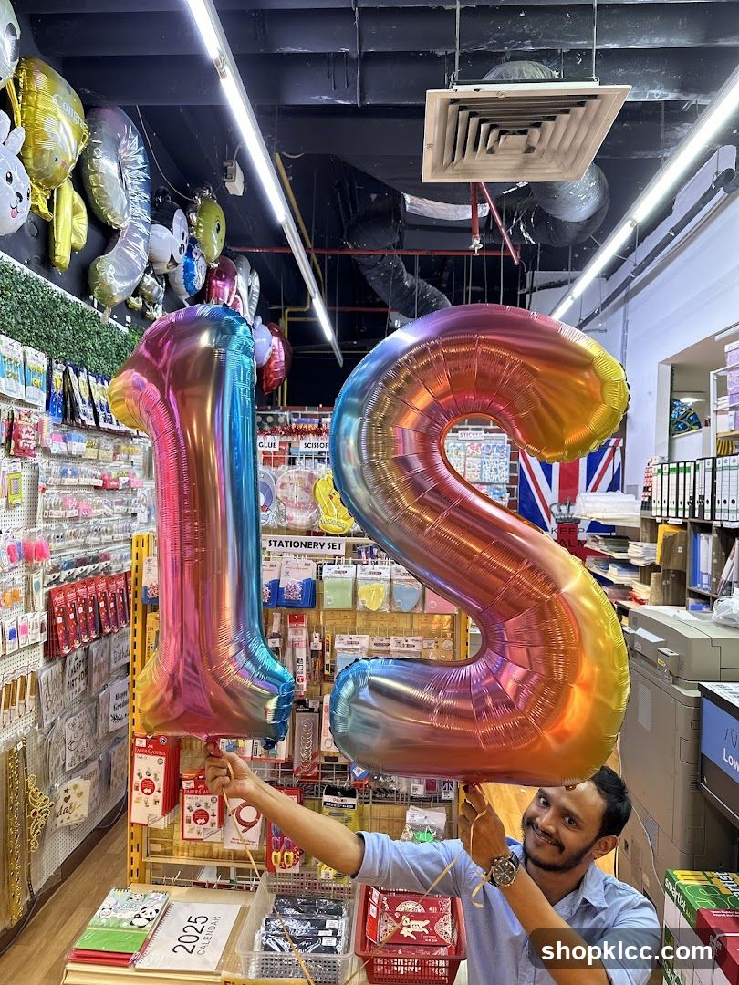 Man holding large number balloons in a store