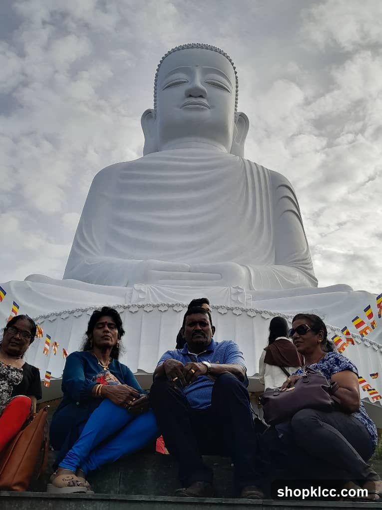 People sitting in front of a large Buddha statue