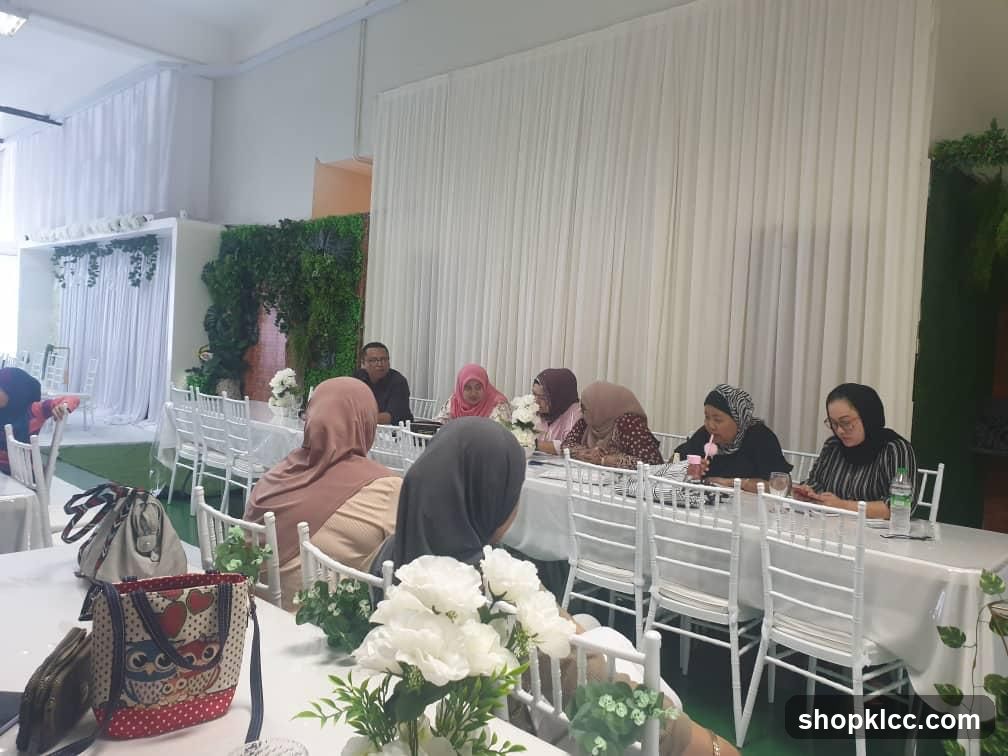 People seated at tables with white chairs and floral decorations