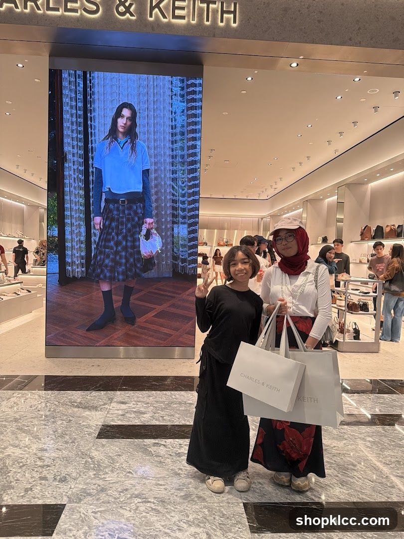 Two people posing in front of a Charles & Keith store display