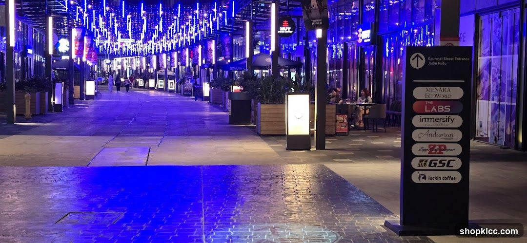 Outdoor walkway with illuminated signs and seating areas