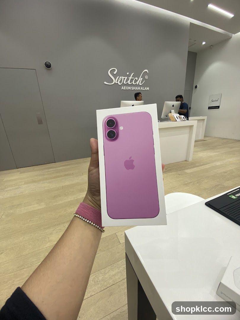 Person holding a pink iPhone box in a store