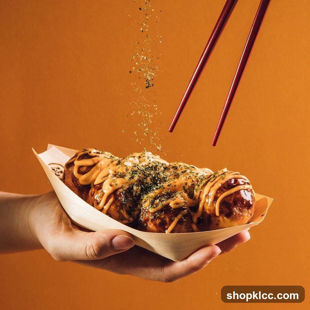 Takoyaki being sprinkled with herbs