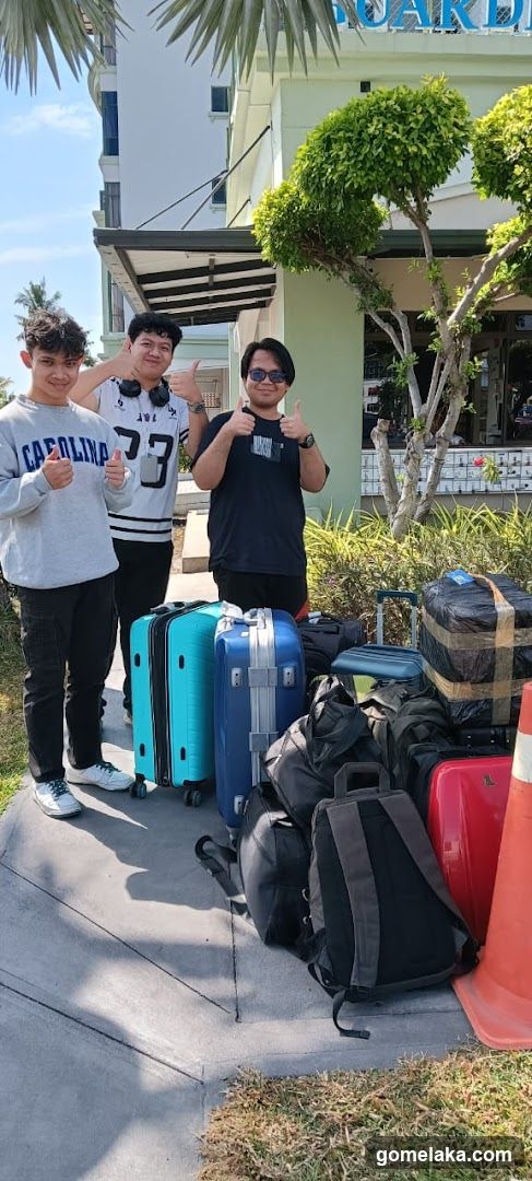 Three individuals posing with luggage outside a building