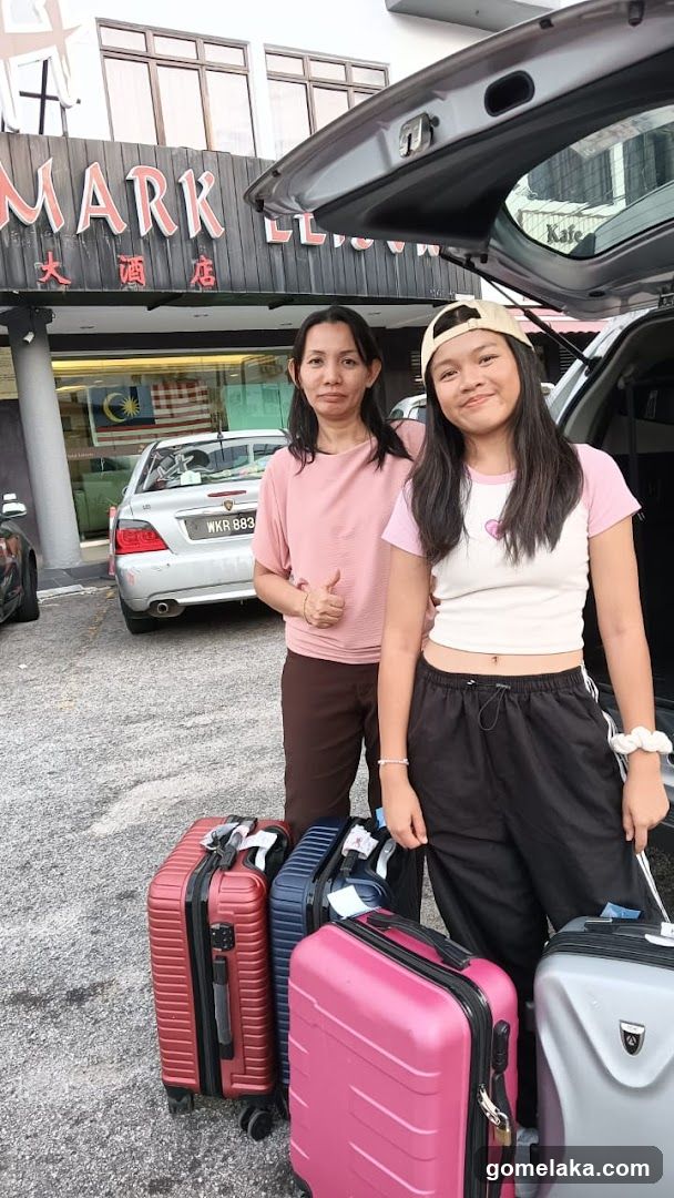 Two individuals with luggage in front of a building