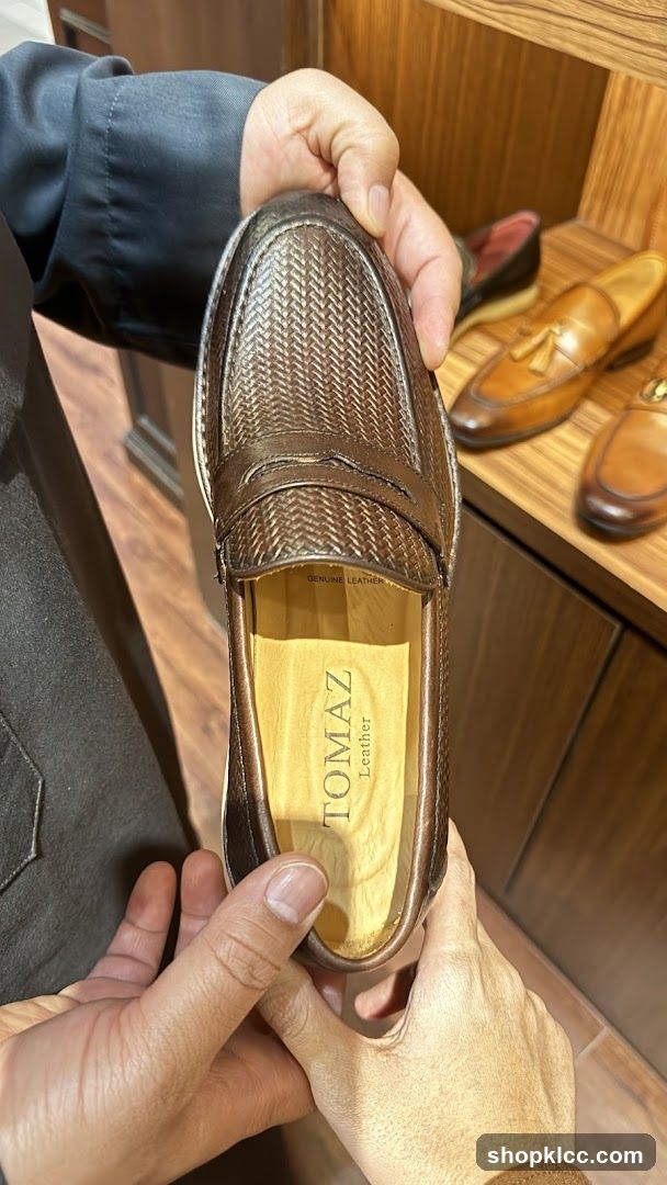 Man holding a brown leather loafer