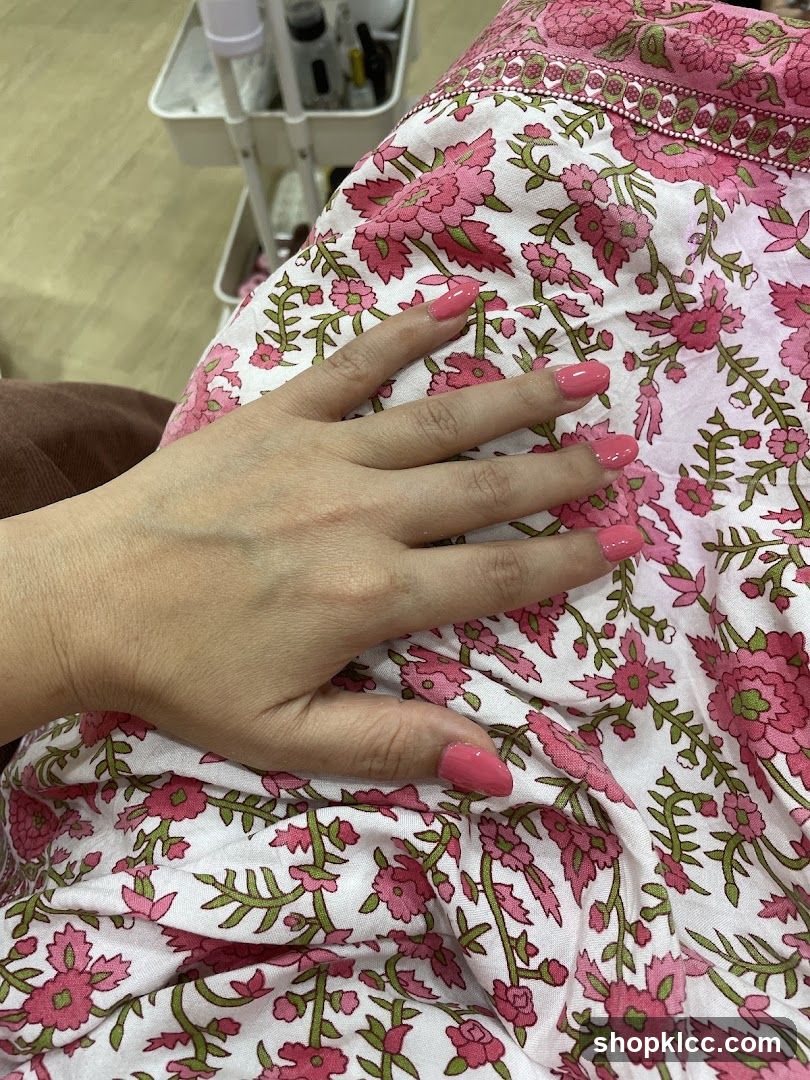 Woman's hand with pink nail polish resting on floral fabric