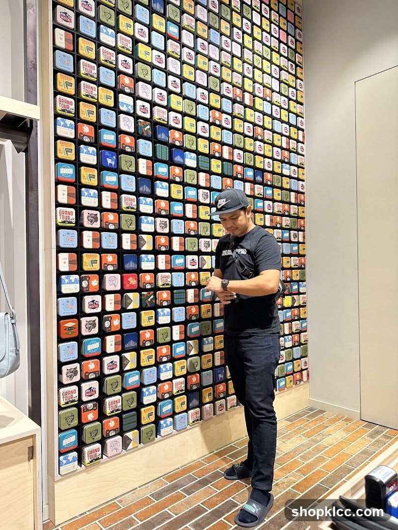 Man looking at watch in front of a wall display of small tins