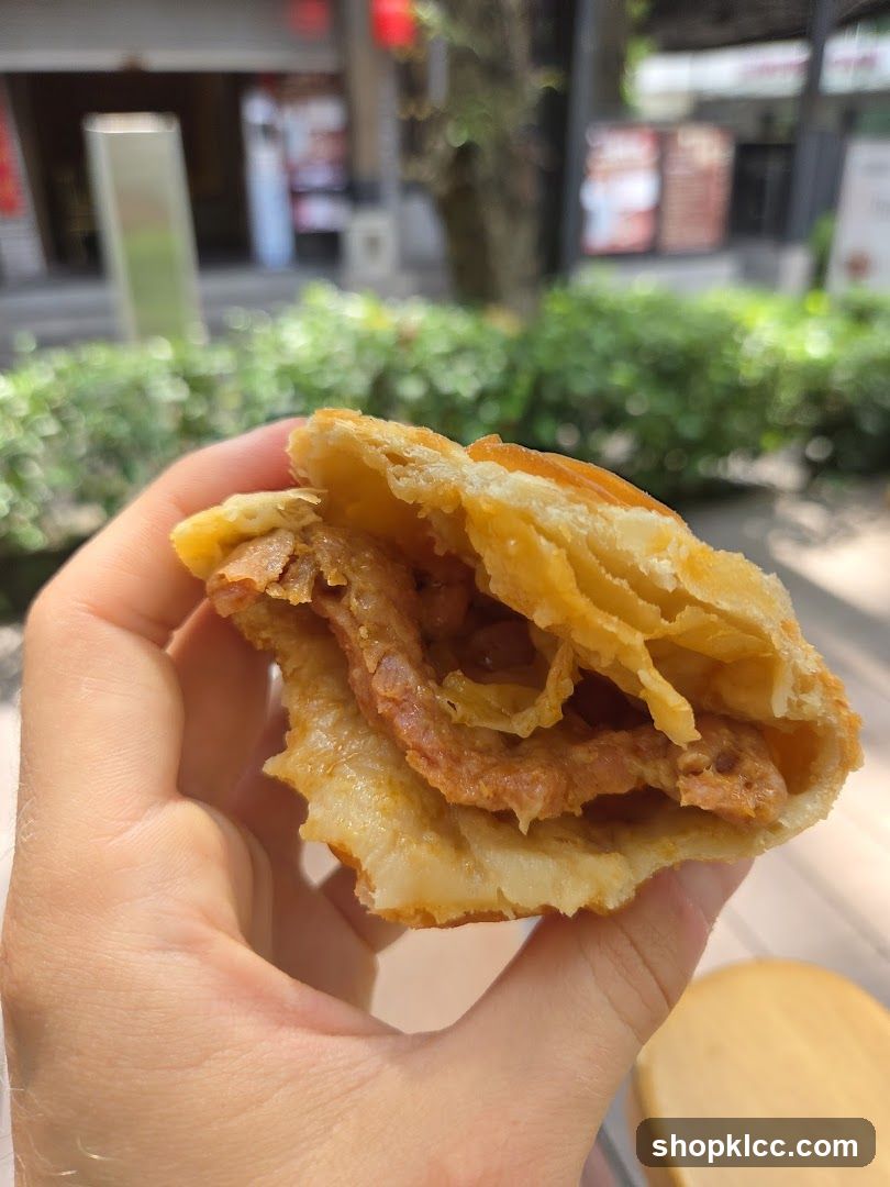 Hand holding a pastry with meat filling