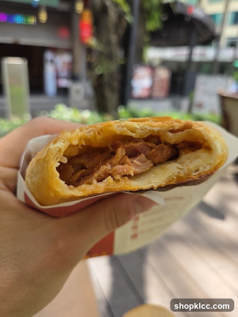 Hand holding a half-eaten pastry sandwich