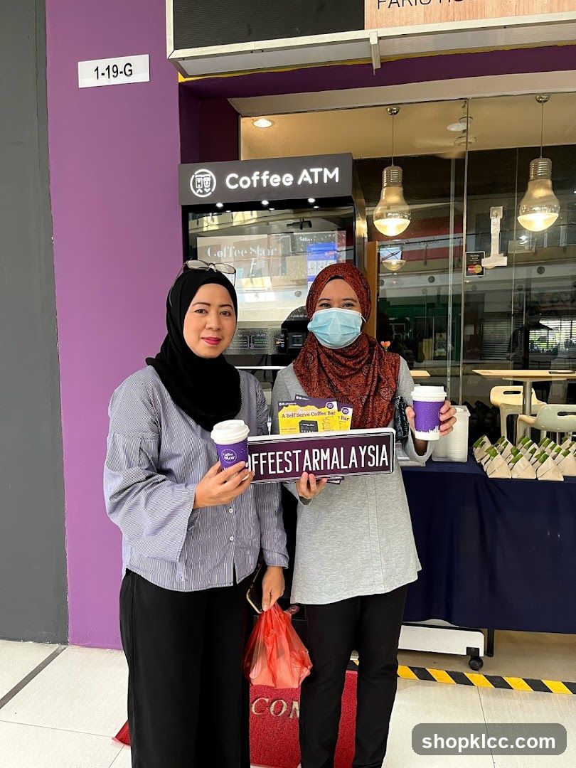 Two women holding coffee cups and a sign