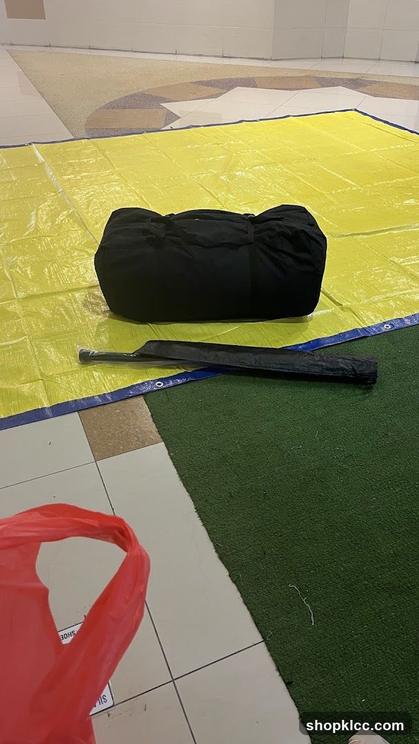 Black duffel bag and umbrella on yellow tarp