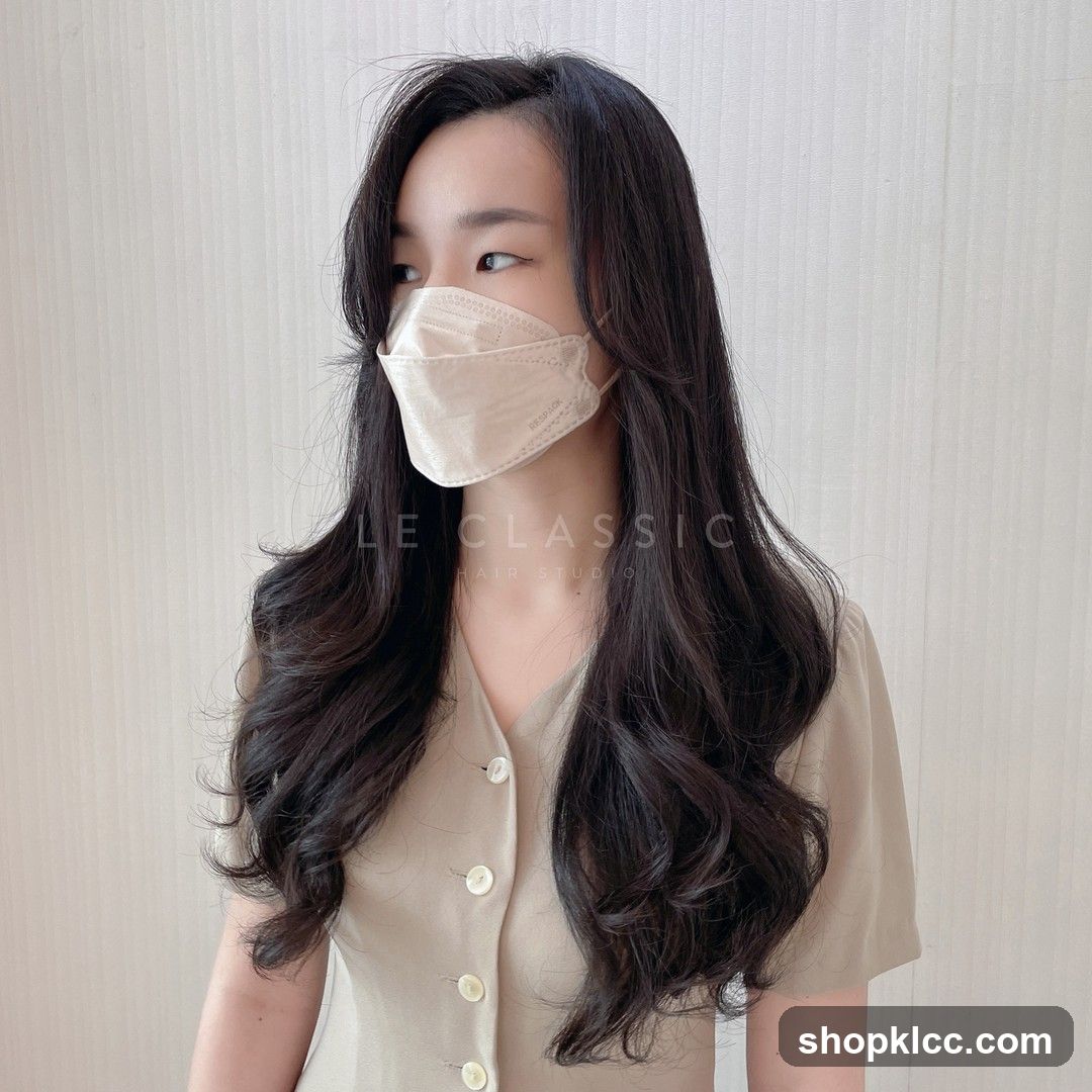 Woman with long, wavy dark hair and a beige mask
