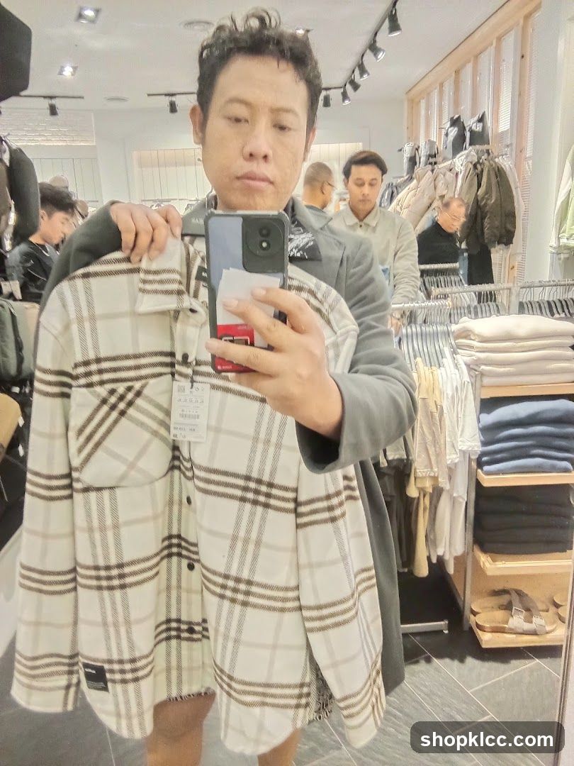 Man holding a plaid shirt in a clothing store