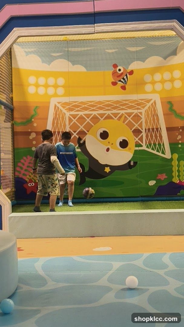 Children playing soccer in a cartoon-themed indoor playground