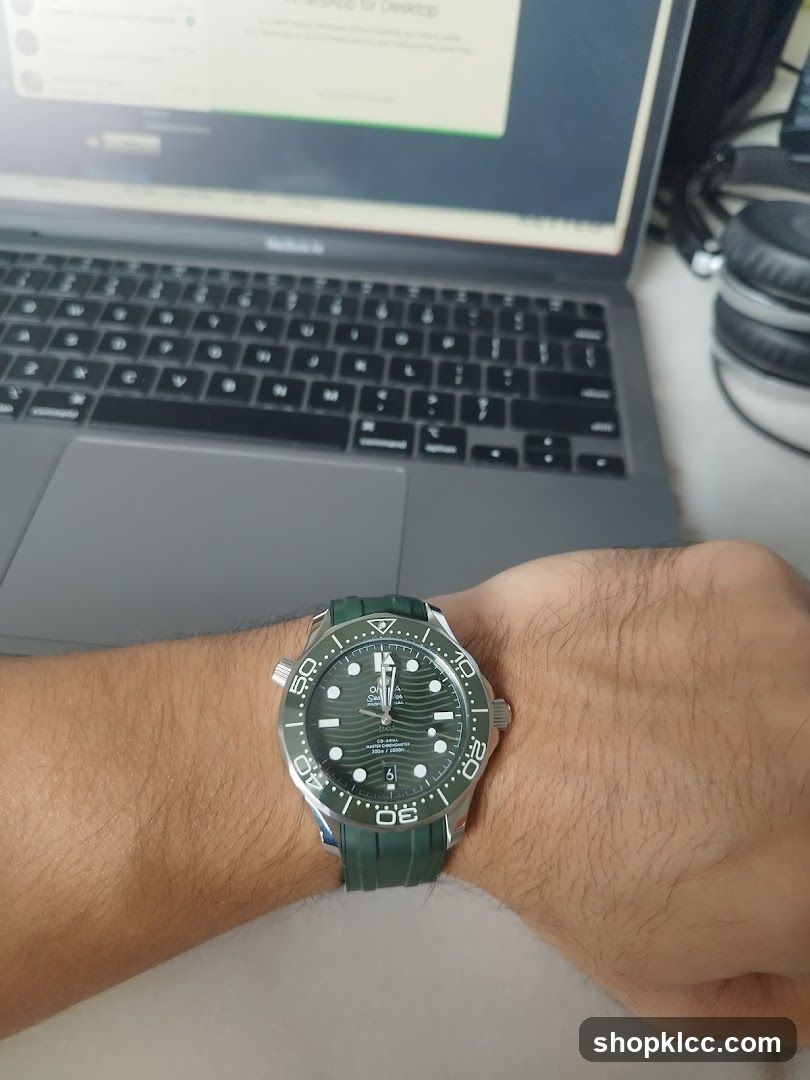 Watch on wrist with laptop in background