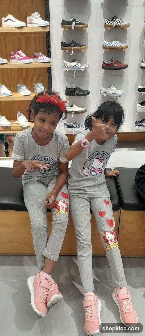 Two girls in Hello Kitty outfits giving thumbs up in a shoe store