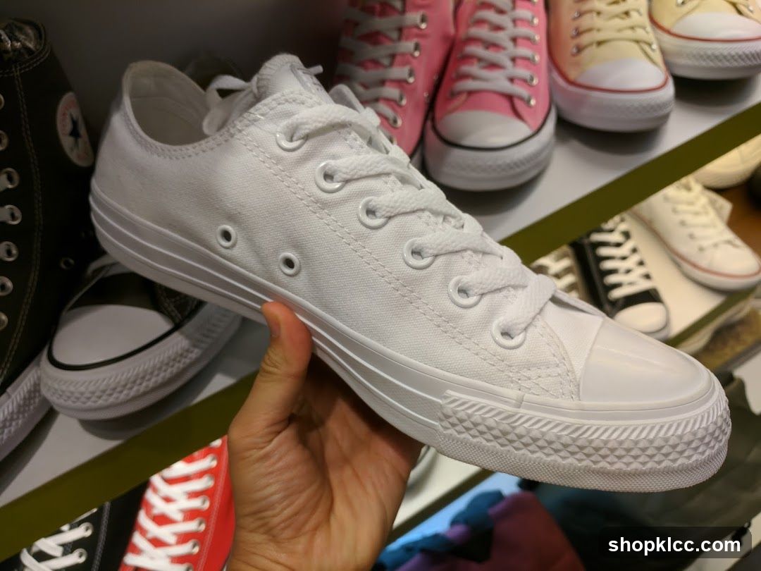 Hand holding white sneakers
