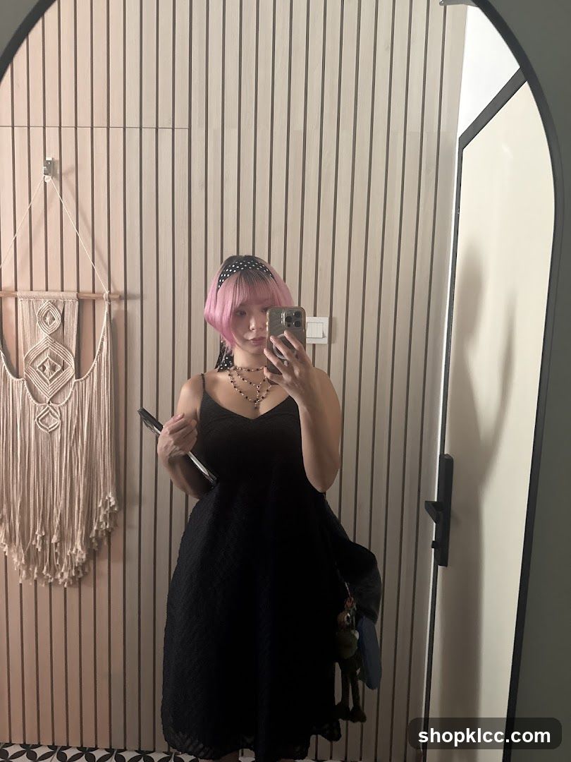 Woman in black dress taking a mirror selfie