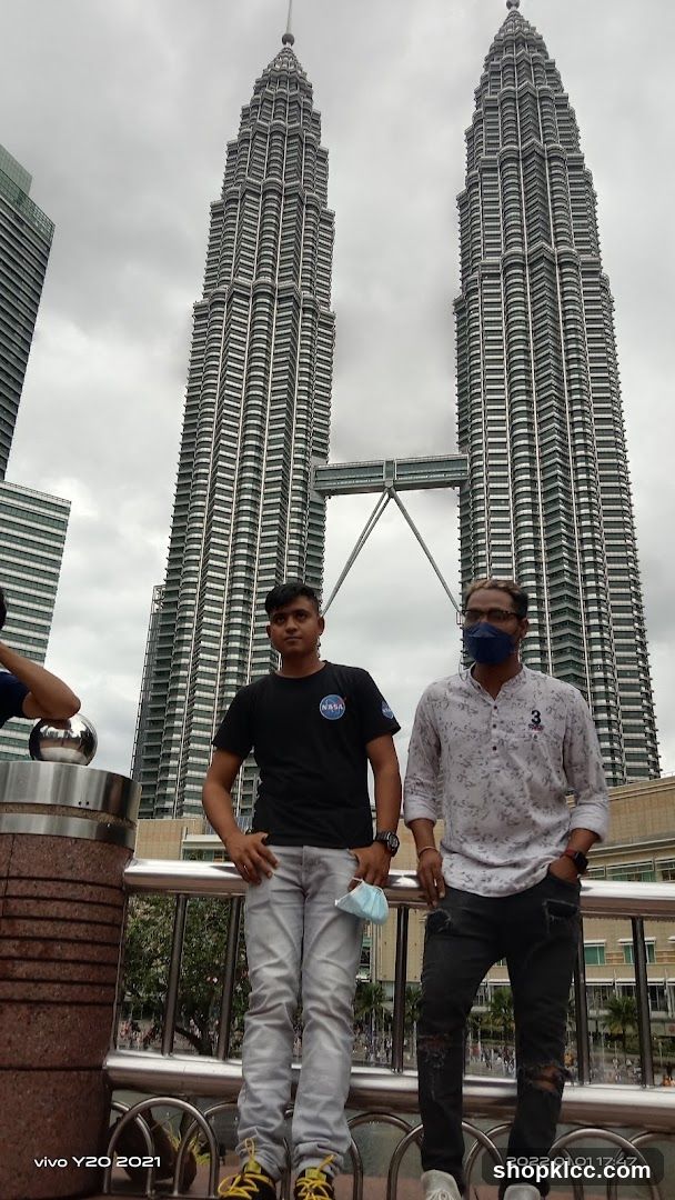 Two men posing in front of the Petronas Towers