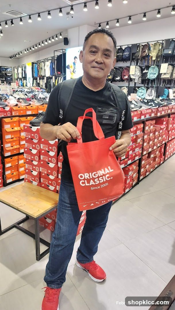 Man holding a red tote bag in a shoe store