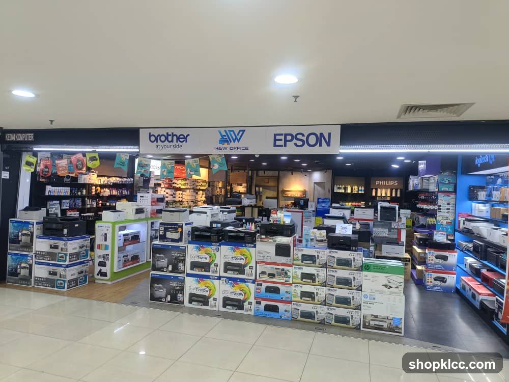 A computer store with various printers and office equipment displayed. Brands like Brother, Epson, and Philips are visible.