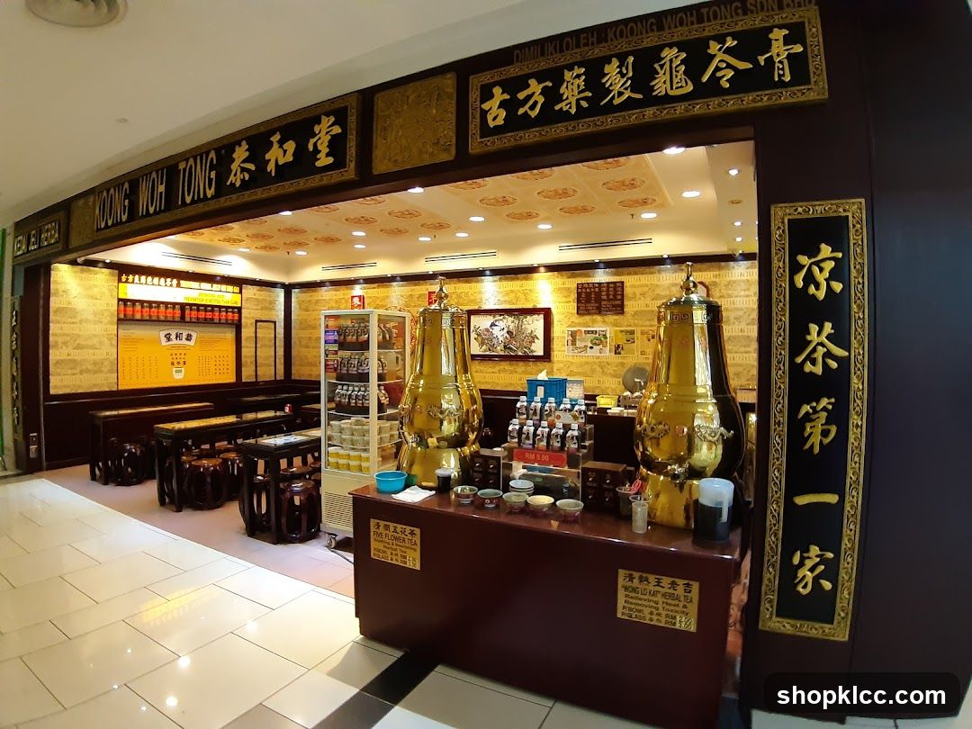 The exterior of a traditional Chinese herbal tea shop. The shop has a dark wood facade with ornate gold lettering. Inside, there are seating areas with wooden tables and stools, display shelves with bottles and jars, and large golden urns. A menu board is visible on the back wall.