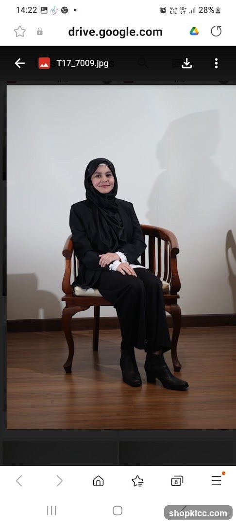 Woman in black suit and hijab sitting on a chair