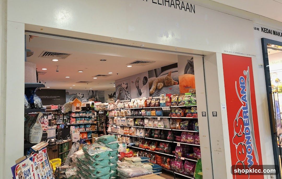 The exterior of a pet supply store with shelves stocked with pet food and accessories visible through the open entrance. A large red sign with the store's name, "Pets Wonderland," is prominently displayed on the right side of the entrance.